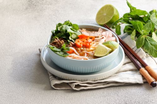 steaming bowl of vietnamese pho showing noodles, herbs, and beef slices