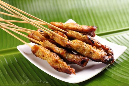 grilled chicken satay skewers served with peanut sauce showing charred edges