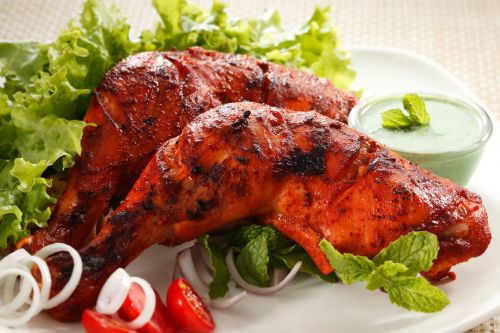 grilled tandoori chicken on platter showing red-orange smoky color