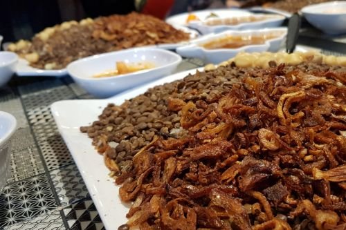 bowl of egyptian koshari showing lentils, rice, and tomato sauce topping