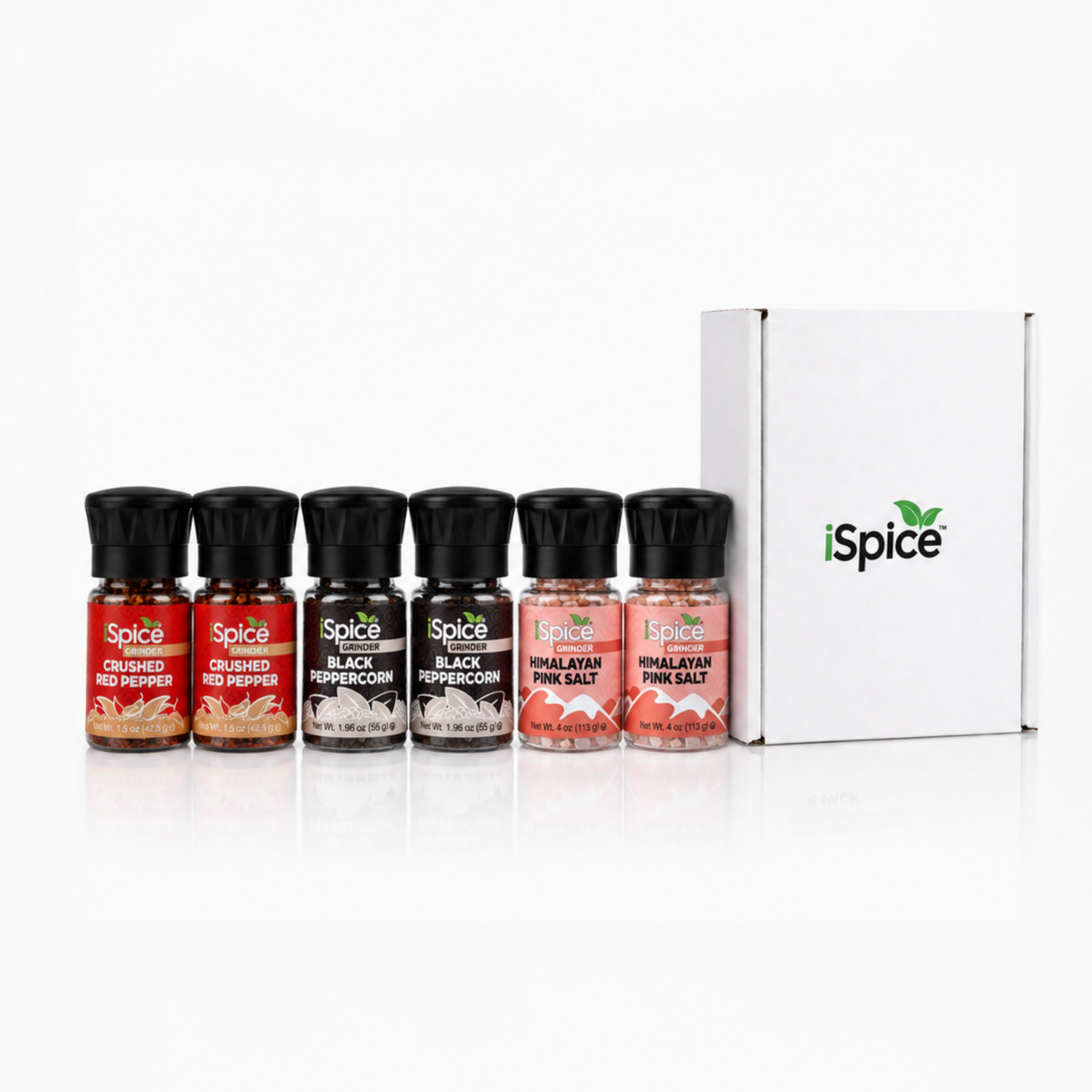 Six small iSpice seasoning bottles with black caps are lined up in front of a white iSpice box on a clean white background. The bottles contain red, brown, black, and pink spices, and the box is white with the green and black iSpice logo.