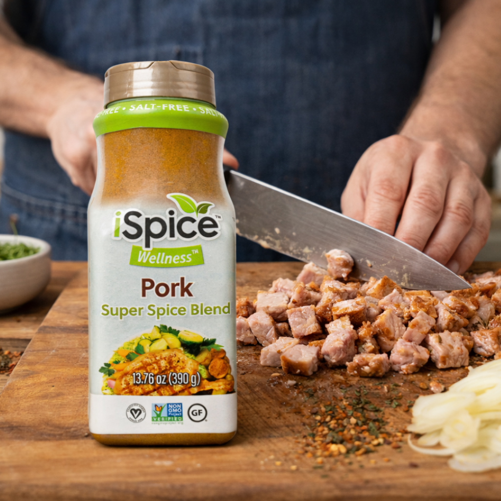 iSpice Wellness Pork Super Spice Blend bottle on a cutting board with chopped pork and a person cutting meat.