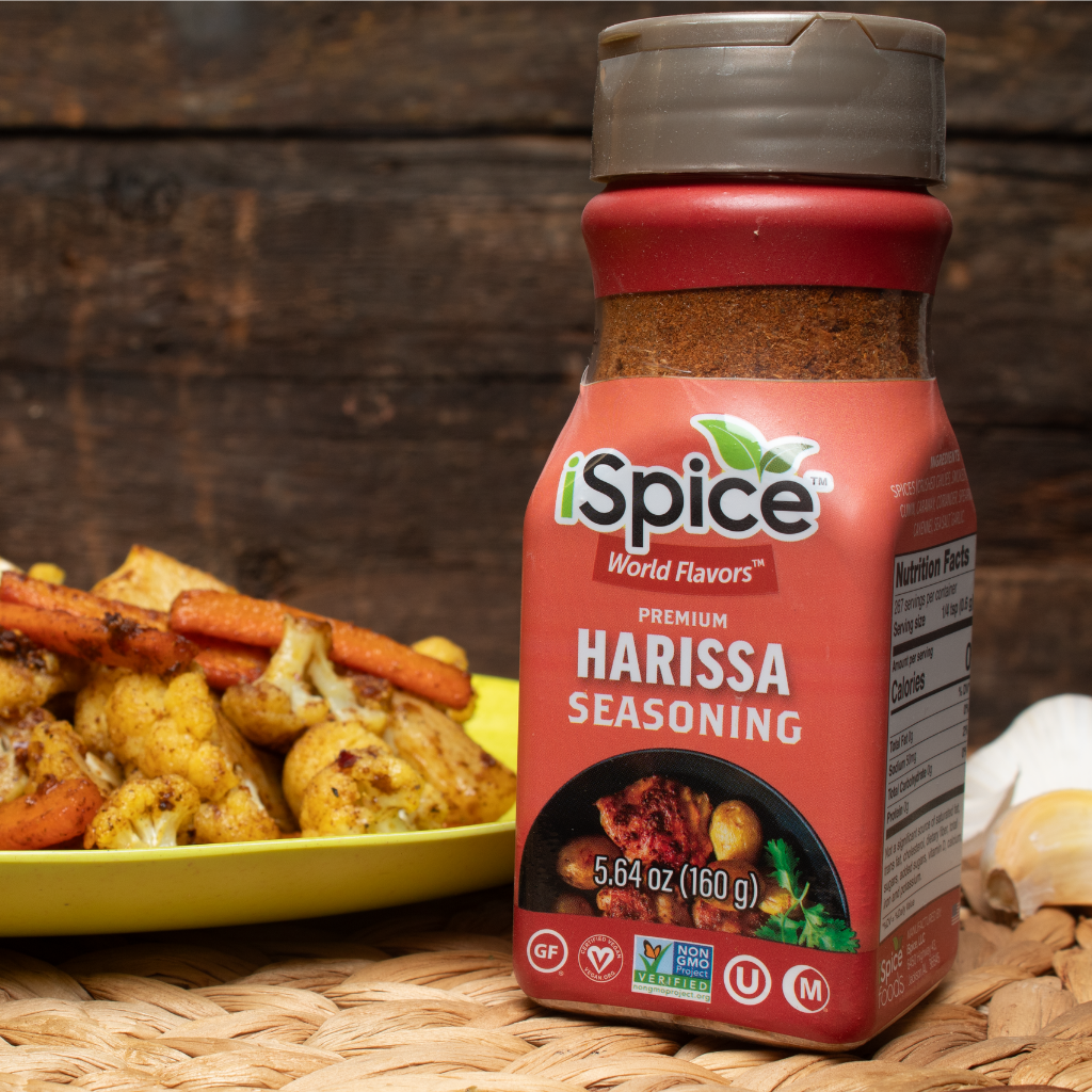 iSpice Harissa seasoning bottle with roasted vegetables on a wooden surface